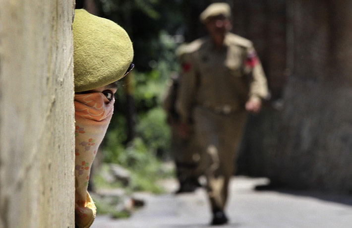 24 hours in pictures: Srinagar, India: A policewoman peeps out from behind a wall during a curfew