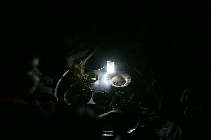 24 hours in pictures: Baghdad, Iraq: A family eats dinner by torchlight during a power cut