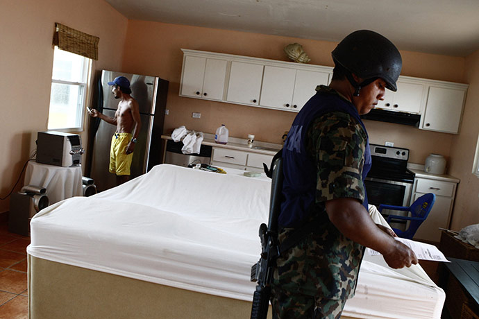 Hurricane Alex: A Mexican Marine fills a report while a resident refuses to leave his house