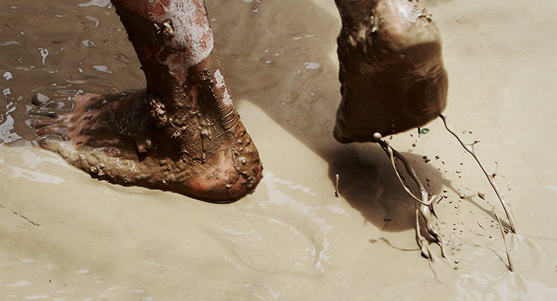 24 Hours: A man walks through a layer of mud after flooding by the Rio Grande