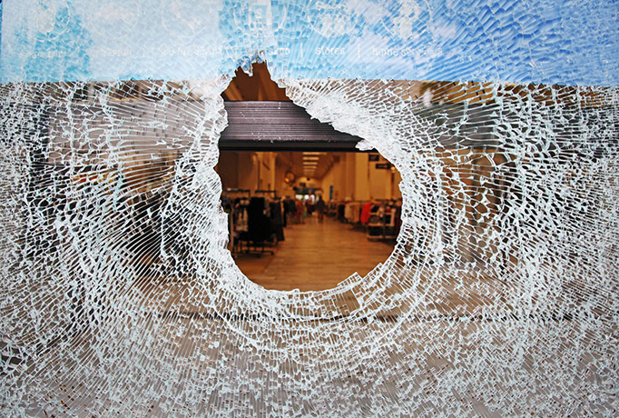 24 Hours: Broken glass in smashed window frames the interior of a store in Oakland