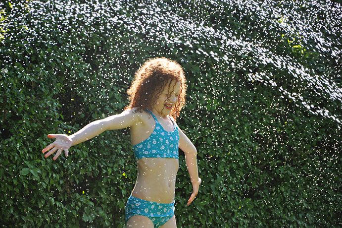 in pictures: summer: girl under garden sprinkler