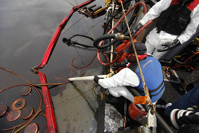Deepwater Horizon: BP oil spill: A cleanup worker vacuums oil 