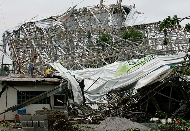 Typhoon Conson: Filipino workers try to dismantle a billboard that collapsed,Manila