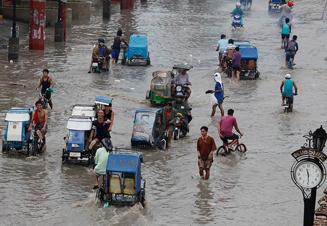 Typhoon Conson: Residents wade through a flooded street at Las Pinas