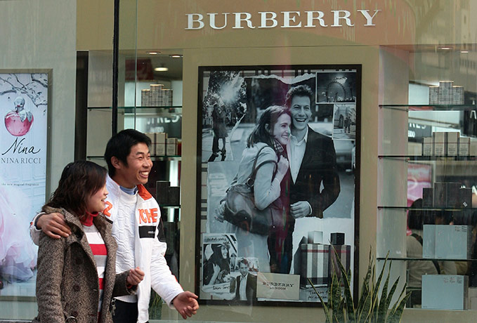 Burberry: A couple walks past a Burberry shop window, China