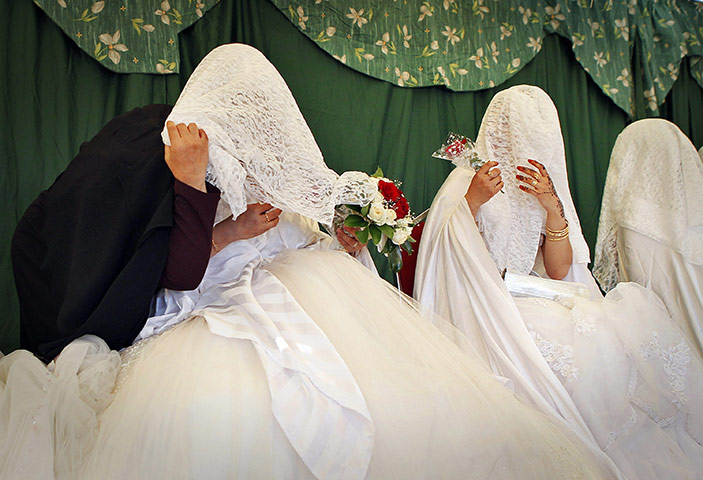 24 Hours in Pictures: A wedding organizer with a bride during a mass wedding ceremony in Amman