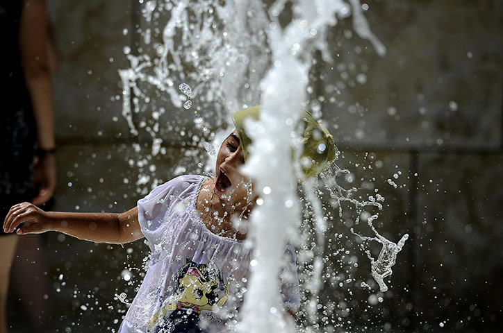 24 hours in pictures: A young girl refreshes herself in a fountain, Rome