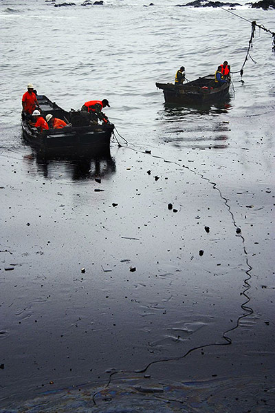 Dalian Oil Spill: Chinese firefighters are seen on boats amongst the an oil spill 