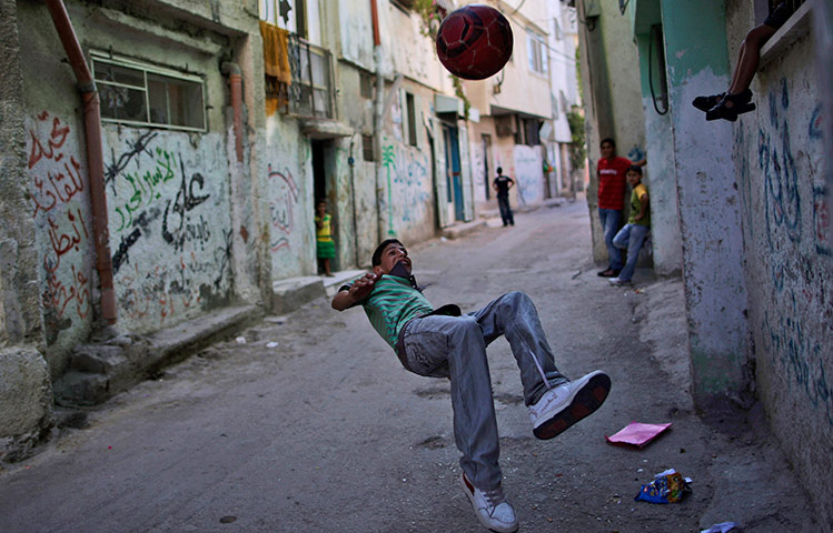 24 hours in pictures: A Palestinian youth plays football in al-Amari refugee camp