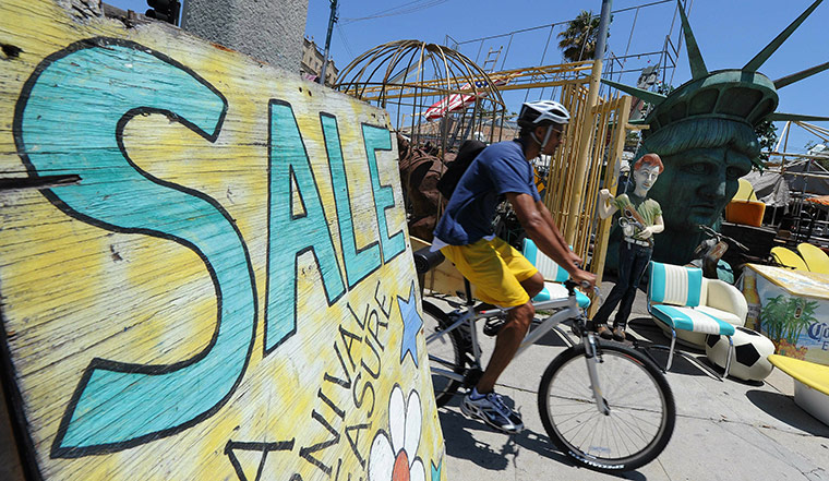 Week in Business: A man rides past a business offering film props on sale in Hollywood