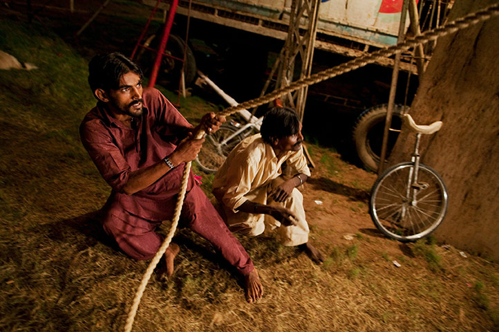 Jan Baz Circus: A circus hand pulls on a rope backstage