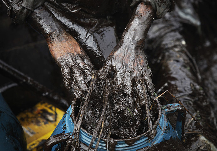 24 hours: A fisherman cleans up oil near a spill site in Dalian, Liaoning province