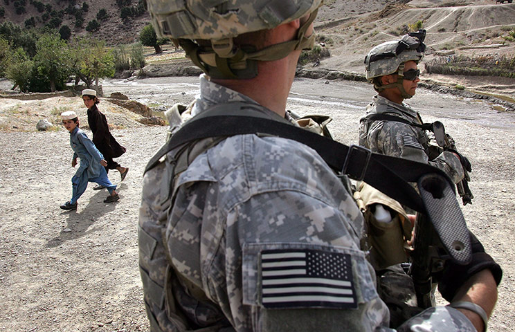 Afghanistan: 16 October 2006: Army snipers patrol past young Afghans in Mundi Kalai