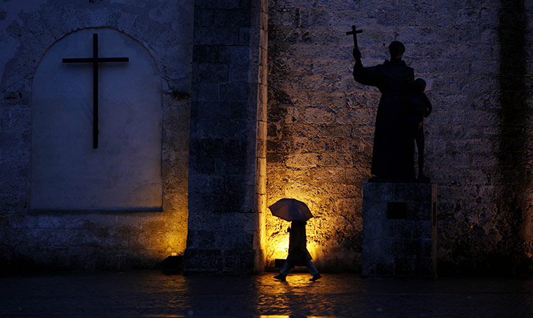 24 hours in pictures: Havana, Cuba: A man walks uses an umbrella