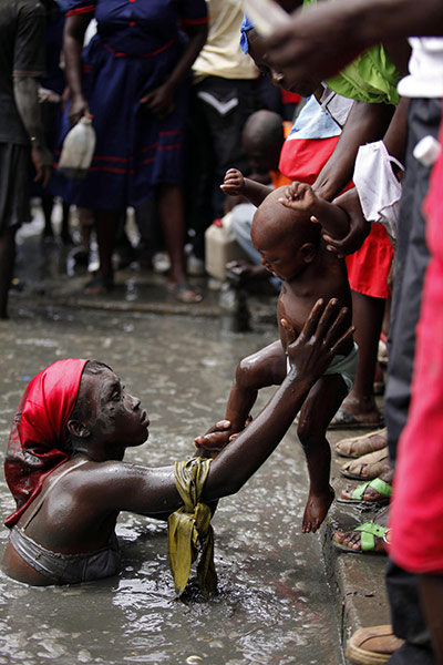 Voodoo in Haiti: A voodoo believer lowers a child into a mud pool 