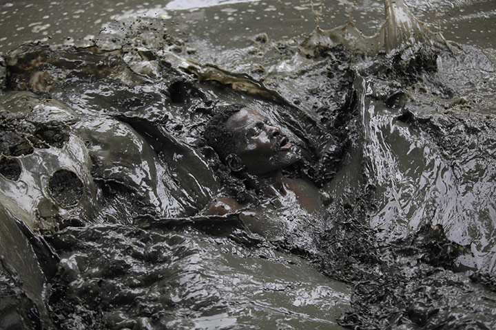 Voodoo in Haiti: A voodoo believer swims in a mud pool during a mass ritual