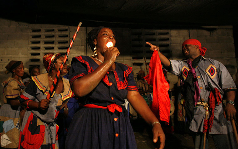 Voodoo in Haiti: A voodoo believer puts a candle into her mouth as she falls into a trance 