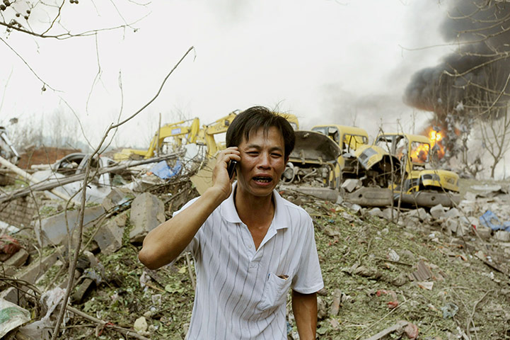 china factory explosion: A worker talks on a mobile phone as he stands near the site of an explosion