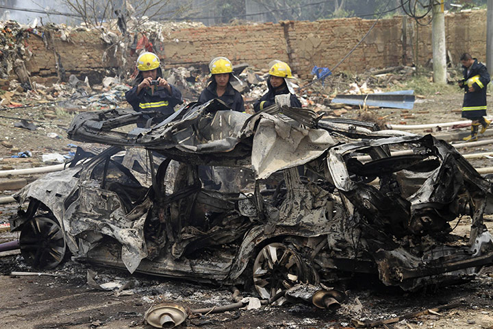 china factory explosion: Firefighters stand next to the wreckage of a vehicle