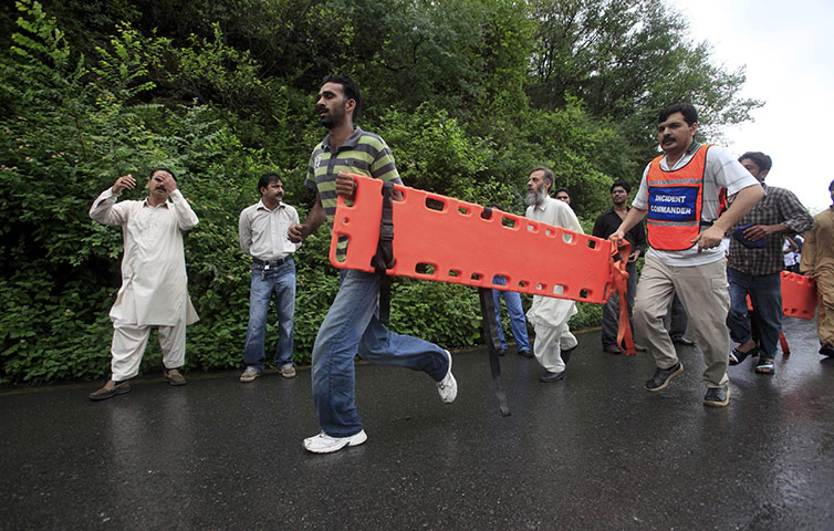 Plane crash in Pakistan: Rescue workers run with a stretcher near the site of the plane crash