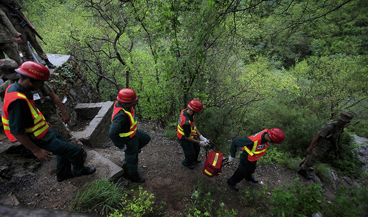 Plane crash in Pakistan: Members of a rescue team make their way through a forest