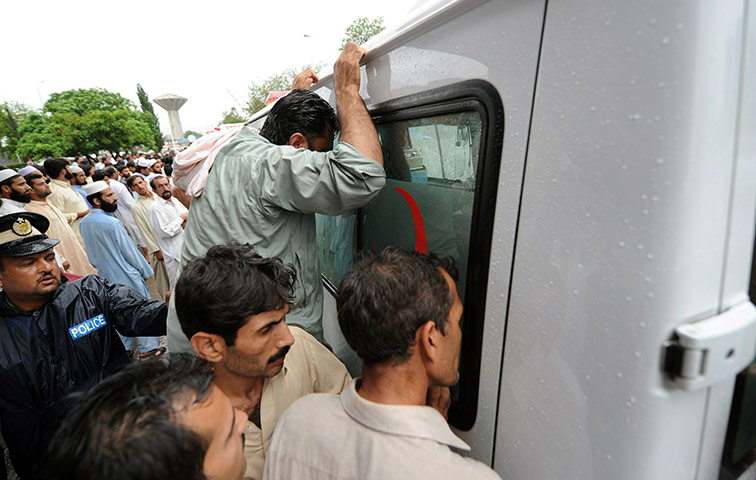 Plane crash in Pakistan: Pakistani men peer through the window of an ambulance