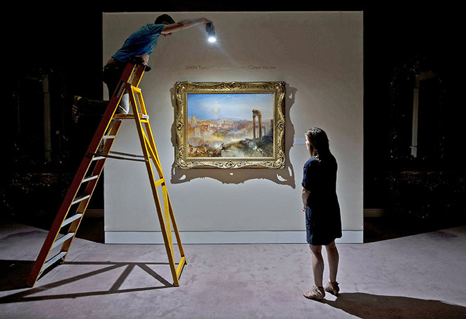 24 Hours in Pictures: A Sotheby's employee holds a flashgun to a JMW Turner masterpiece
