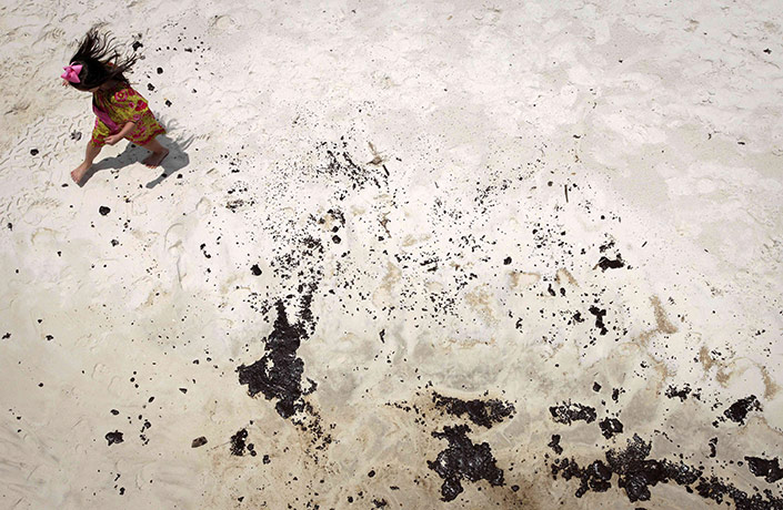 24 Hours in Pictures: An unidentified girl avoids puddles of oil on the beach in Gulf Shores
