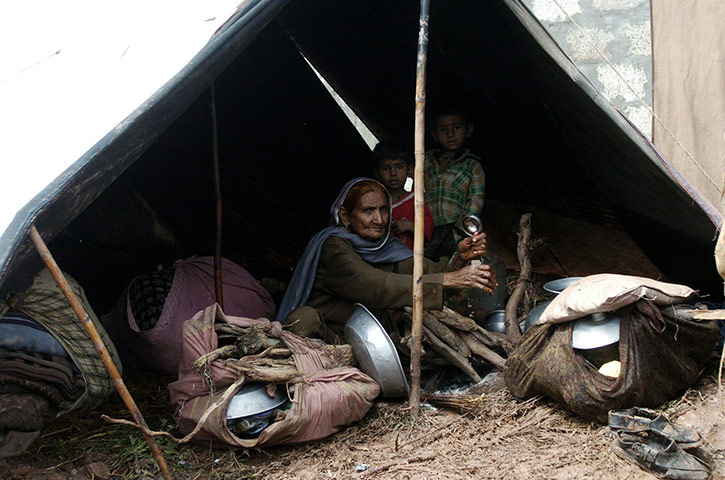 Pakistan floods: An elderly Pakistani woman sits with two children in a tent