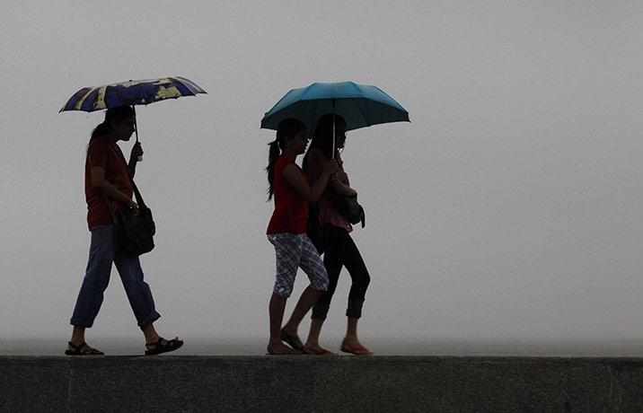 24 hours in pictures: Mumbai, India: Girls walk on a seaside promenade as it rains