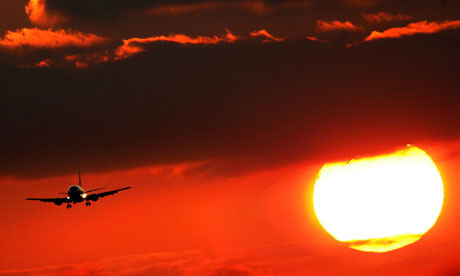 An aeroplane in front of the setting sun. Climate change global warming