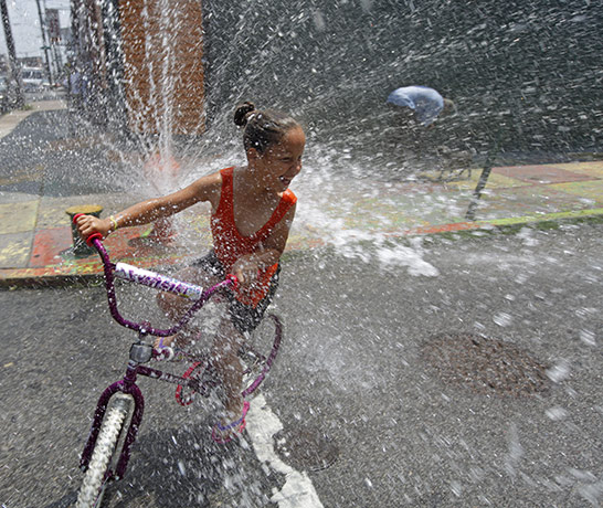 24 hours in pictures: Philadelphia , US: A girl cools off in spraying water from a fire hydrant