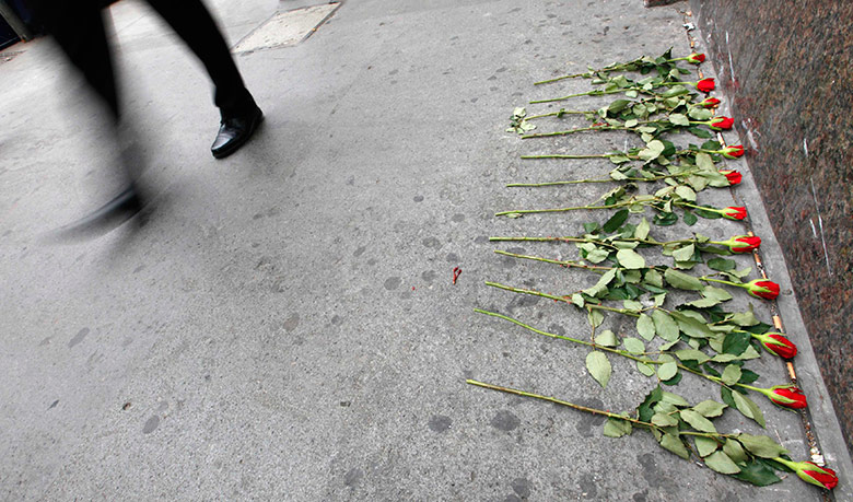 7/7 5th annivesary: A commuter walks past a row of roses left outside Aldgate Underground 7/7