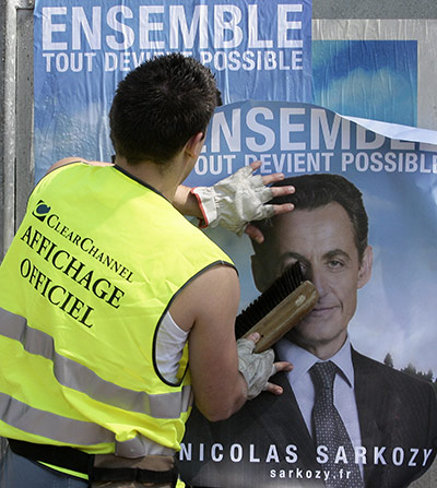 Bettencourt case 2: An employee sticks posters of presidential candidate Nicolas Sarkozy
