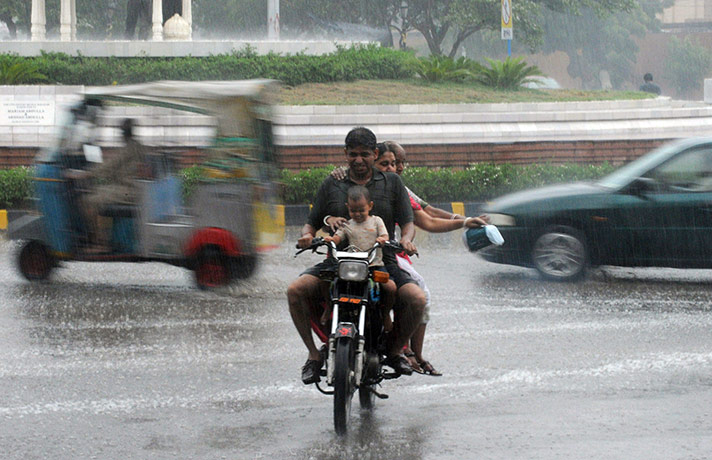 Monsoon in India: Commuters travel during rain in Karachi