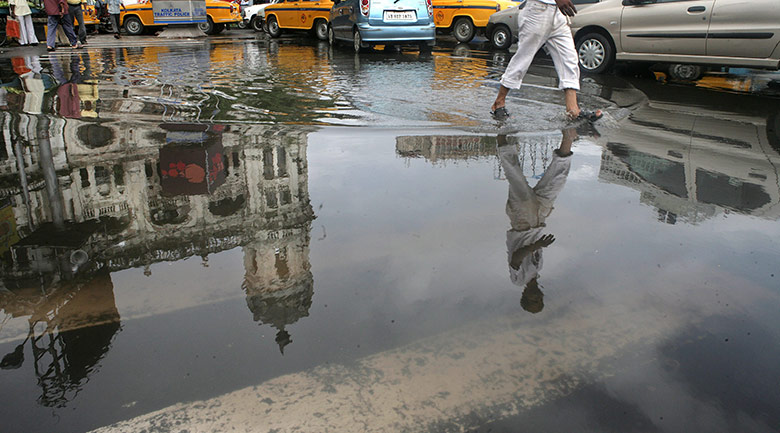 Monsoon in India: A commuter walks through a huge pool of rainwater in Kolkata