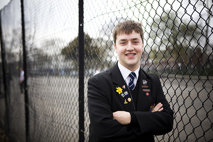 Fair Trade Town: A young man stands by a school fence