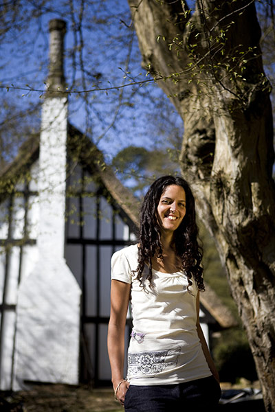 Fair Trade Town: A young woman stands outside a rural house looking to camera