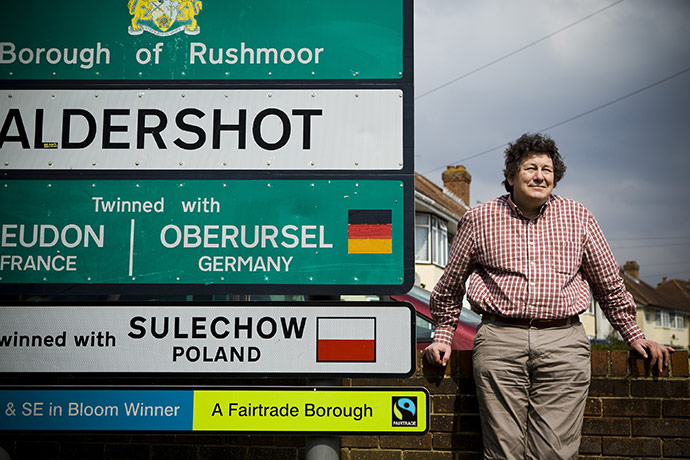 Fair Trade Town: A middle aged man stands by a sign to Aldershot