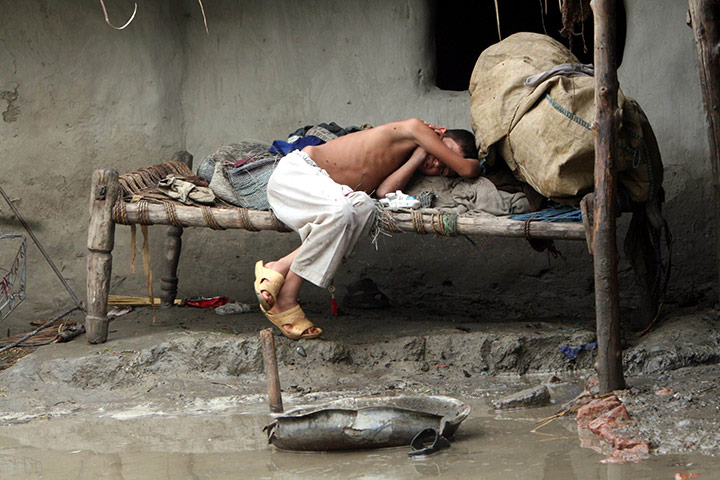 Pakistan floods: An exhausted boy has a nap in his flooded house in Peshawar