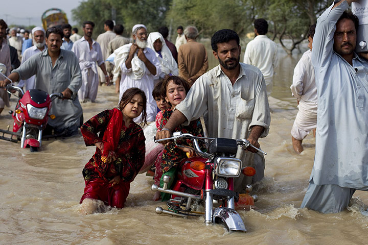 Pakistan floods: A man evacuates his children through waist-deep waters in Nowshera
