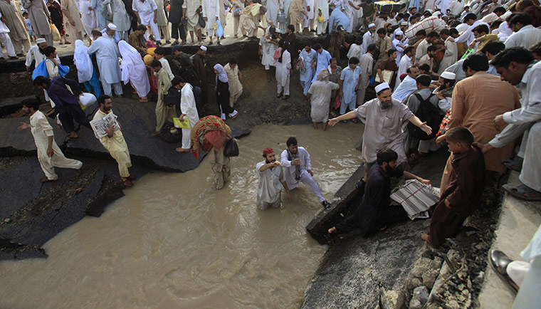 Pakistan floods: Men assist residents in crossing the Islamabad Peshawar toll way