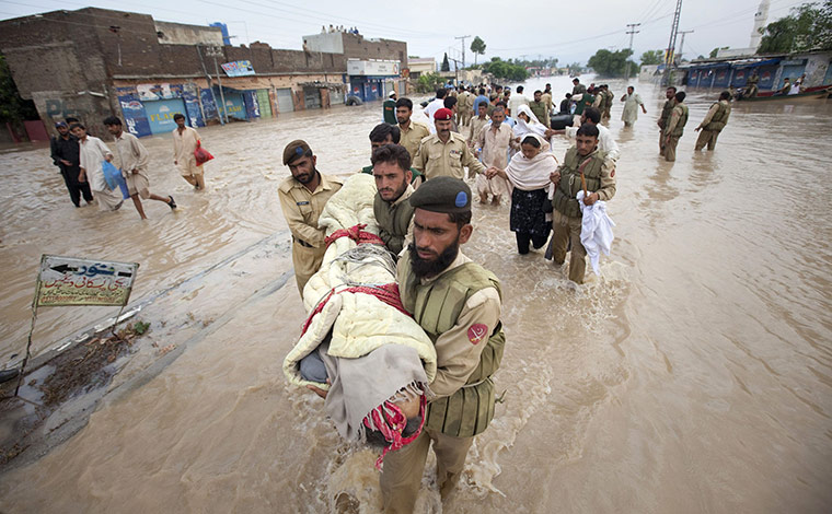 Pakistan floods: Army soldiers carry the body of a dead man to higher ground 
