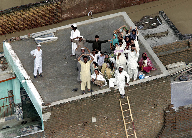 Pakistan floods: Stranded villagers wait for helicopters on the roof of a house in Nowshera