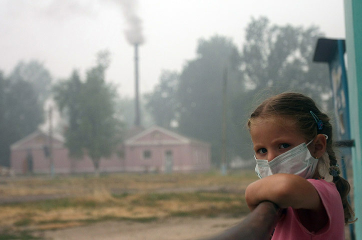 24 hours: Beloomut, Russia: A girl wearing a mask looks out from her balcony