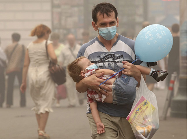 Moscow smog: A man carries a child wearing medical masks to protect from smog in Moscow