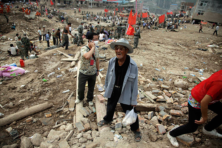 China update: An elderly Chinese man stands on the debris while rescue operation go on
