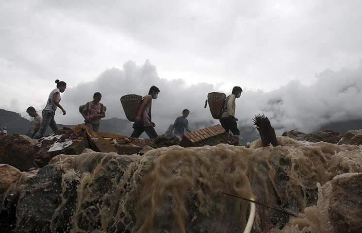 24 hours: Zhouqu, China: Residents walk through water flowing after a mudslide