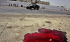 US soldiers drive past a pool of blood from a car bomb in Baghdad during October 2006
